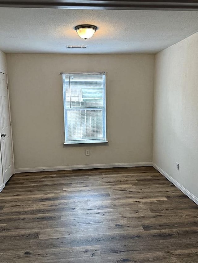 10028 Quail Glen Dr, Fort Worth, TX 76140 - spare room featuring dark wood-type flooring, baseboards, and a textured ceiling