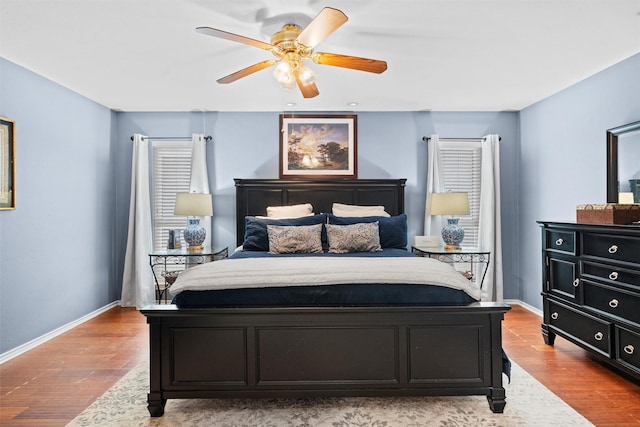 bedroom with wood finished floors, baseboards, and multiple windows
