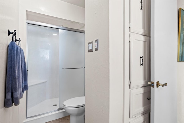 full bath with a stall shower, toilet, and tile patterned floors