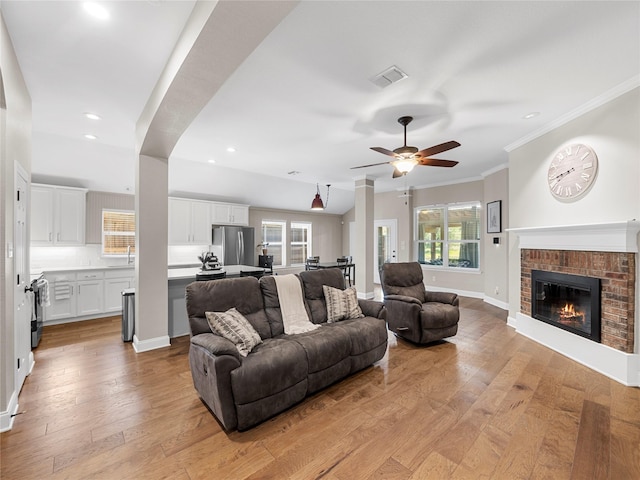 2135 Highland Dr, Wylie, TX 75098 - living room with ceiling fan, light wood-type flooring, ornamental molding, recessed lighting, and a brick fireplace