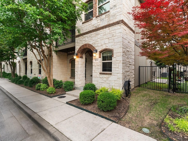 8821 Whitehead St, Mckinney, TX 75070 - doorway to property with stone siding, fence, and a balcony