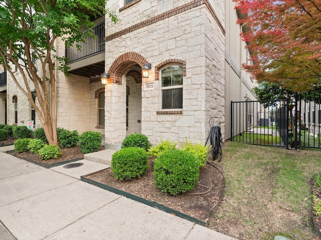 8821 Whitehead St, Mckinney, TX 75070 - view of exterior entry featuring a balcony, stone siding, fence, and a gate
