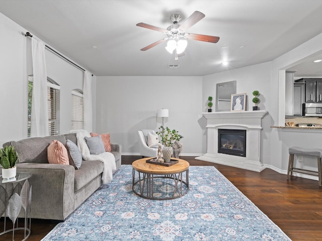 8821 Whitehead St, Mckinney, TX 75070 - living room featuring dark wood-style flooring, ceiling fan, a glass covered fireplace, and baseboards