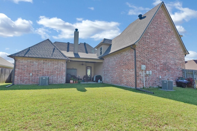 rear view of property with a ceiling fan, cooling unit, a chimney, and brick siding