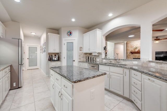 kitchen with a sink, stainless steel appliances, decorative backsplash, white cabinetry, and a kitchen island