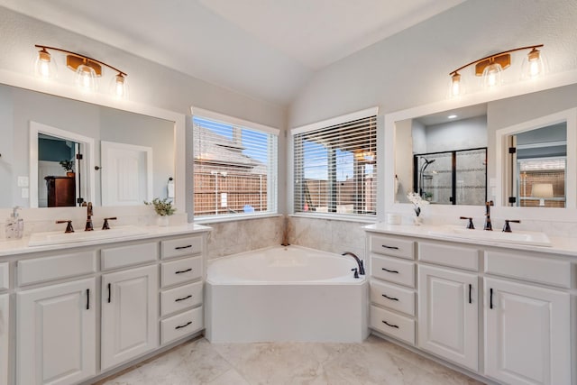 bathroom with lofted ceiling, a stall shower, a garden tub, two vanities, and marble finish flooring