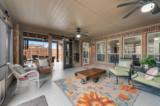 sunroom featuring a ceiling fan and a barn door
