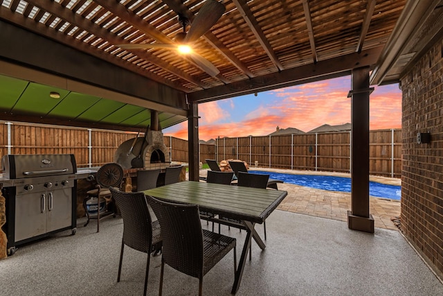 patio terrace at dusk with a fenced backyard, a pergola, area for grilling, and outdoor dining space
