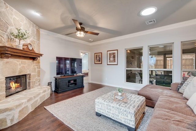 living area with ornamental molding, ceiling fan, a fireplace, dark wood-style floors, and baseboards