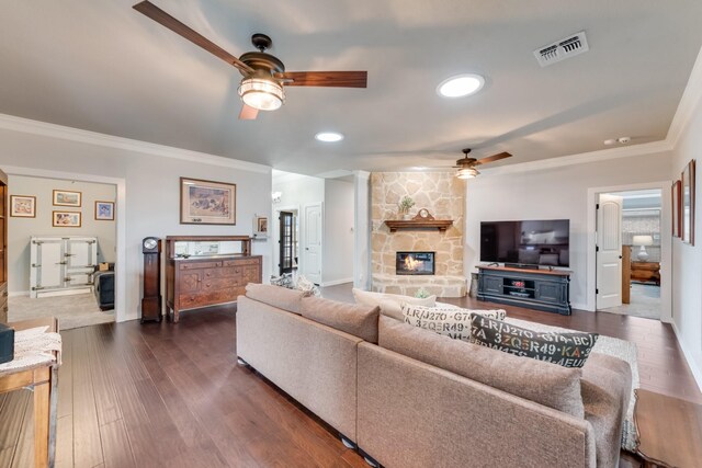 living room with ceiling fan, crown molding, a fireplace, dark wood finished floors, and baseboards