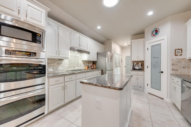 kitchen featuring appliances with stainless steel finishes, decorative backsplash, a center island, white cabinets, and recessed lighting