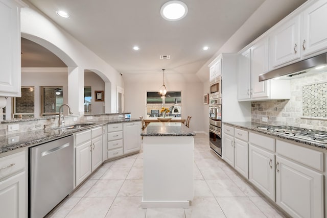 kitchen featuring stainless steel appliances, a sink, under cabinet range hood, decorative backsplash, and white cabinets