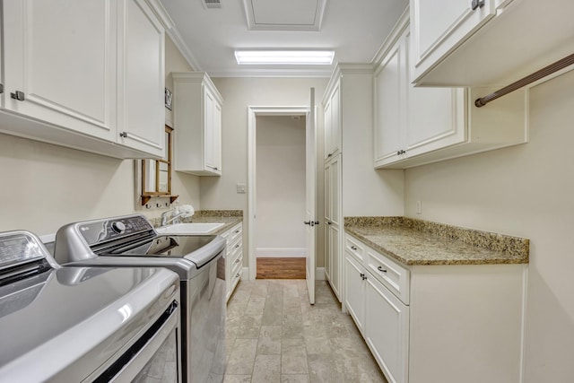 laundry area featuring separate washer and dryer, cabinet space, light stone finish floors, and baseboards