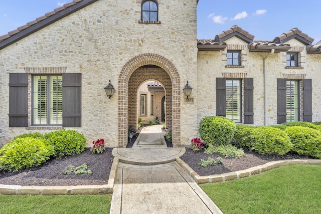 entrance to property featuring a tile roof and stone siding