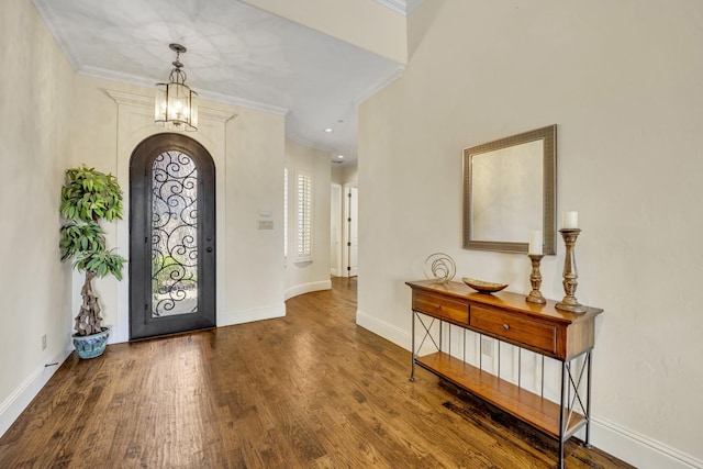 entrance foyer featuring ornamental molding, wood finished floors, baseboards, and arched walkways