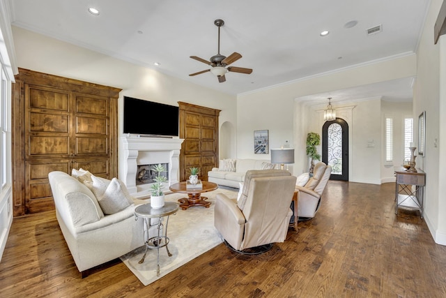 living area with arched walkways, ceiling fan, dark wood finished floors, a fireplace with raised hearth, and recessed lighting