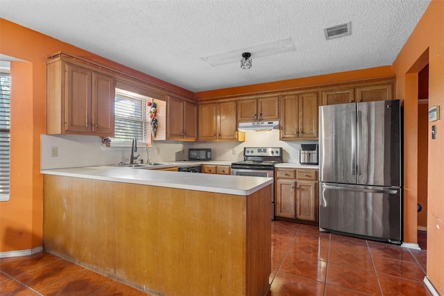 4627 Lexington St, Bellmead, TX 76705 - kitchen featuring stainless steel appliances, under cabinet range hood, a peninsula, brown cabinets, and a sink