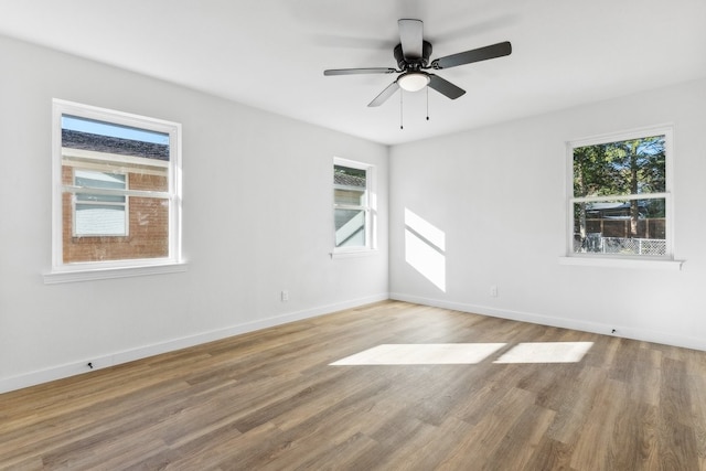 empty room with wood finished floors, ceiling fan, and baseboards