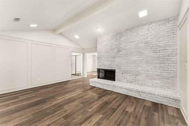 unfurnished living room with a fireplace, dark wood finished floors, brick wall, and a decorative wall