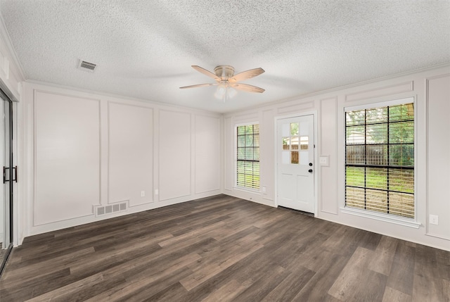 foyer entrance featuring a decorative wall, ceiling fan, dark wood-style floors, and a textured ceiling
