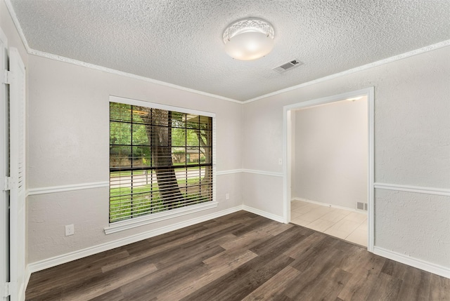 empty room featuring a textured ceiling, wood finished floors, a textured wall, ornamental molding, and baseboards