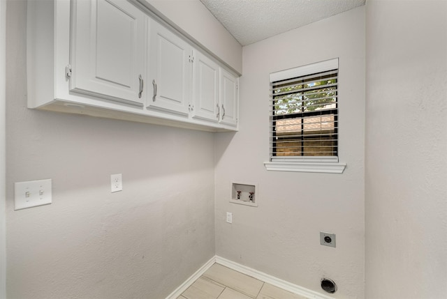 laundry room with cabinet space, hookup for an electric dryer, baseboards, hookup for a washing machine, and a textured ceiling
