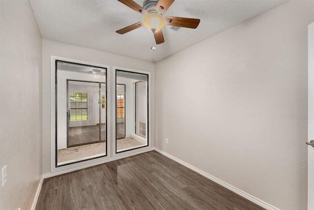 unfurnished room with baseboards, dark wood finished floors, ceiling fan, and a textured ceiling