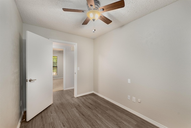 spare room with a textured ceiling, dark wood-style flooring, baseboards, and ceiling fan