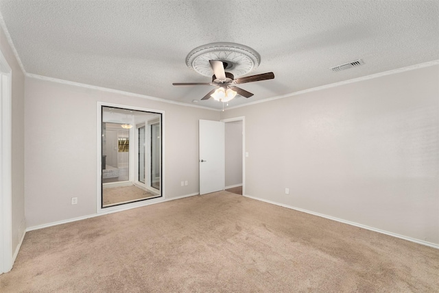 unfurnished room with a textured ceiling, carpet, ceiling fan, crown molding, and baseboards