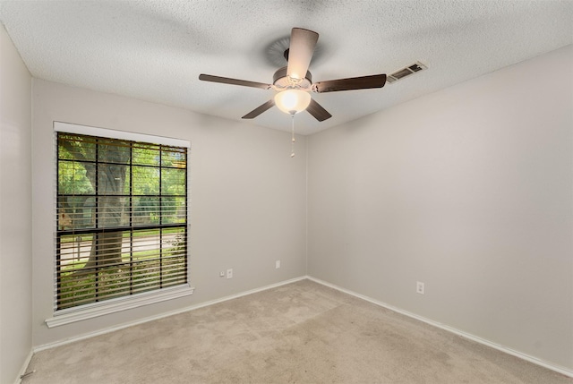 empty room featuring light colored carpet, a ceiling fan, a textured ceiling, and baseboards