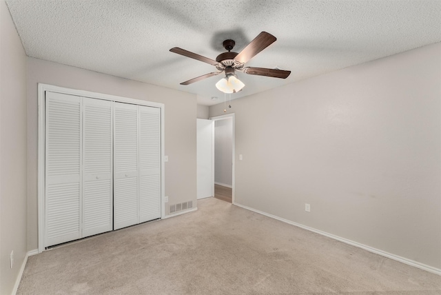 unfurnished bedroom featuring carpet, a closet, baseboards, a ceiling fan, and a textured ceiling