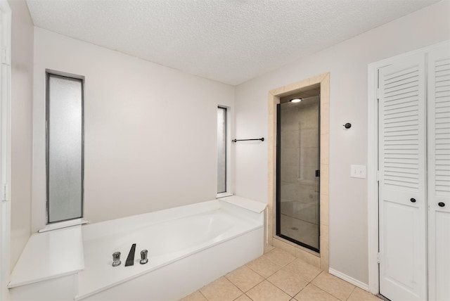 bathroom featuring a garden tub, a stall shower, tile patterned floors, a closet, and a textured ceiling
