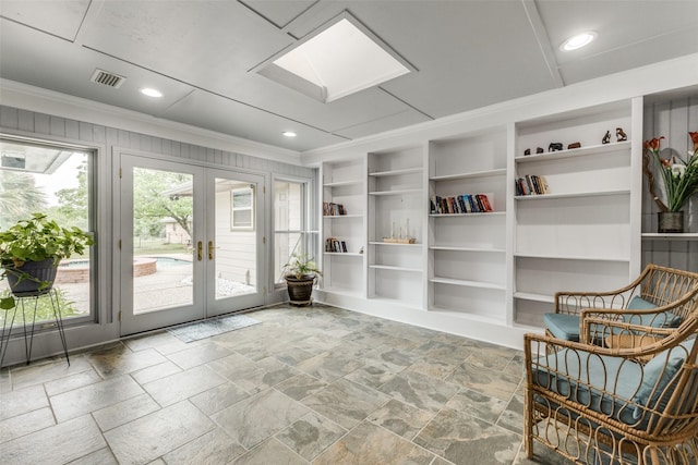 living area with ornamental molding, built in shelves, french doors, a skylight, and stone finish flooring
