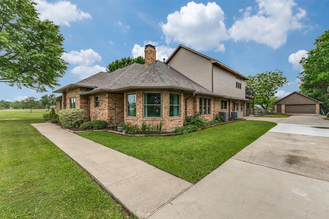 view of front of house featuring brick siding, a chimney, a front lawn, and an outdoor structure