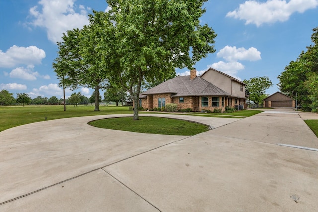 traditional home featuring curved driveway, a front yard, brick siding, and a chimney
