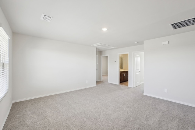empty room featuring light colored carpet and baseboards