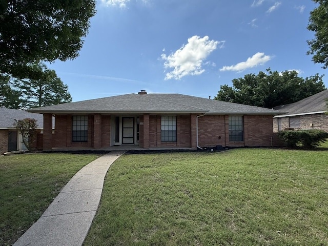 view of front facade with brick siding, a front yard, and a shingled roof