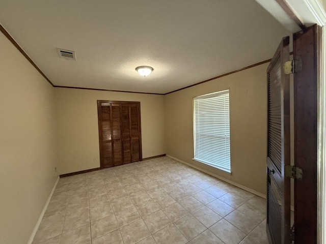 empty room with crown molding, light tile patterned flooring, and baseboards