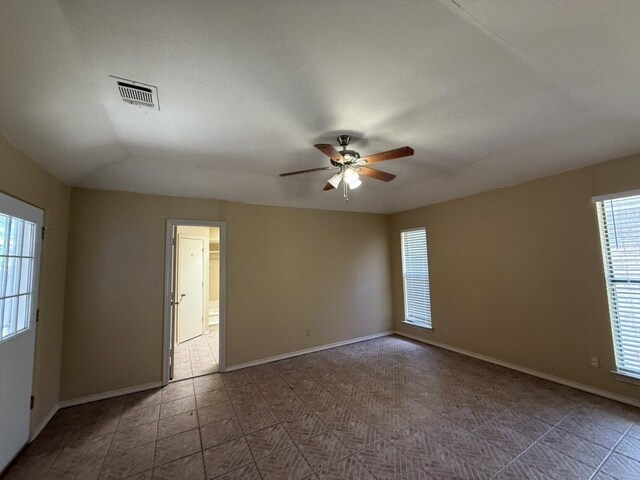 tiled spare room featuring ceiling fan and baseboards