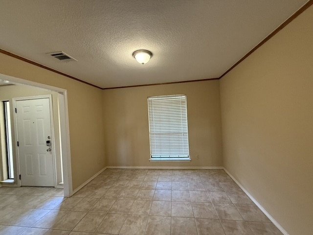 spare room with crown molding, light tile patterned floors, a textured ceiling, and baseboards