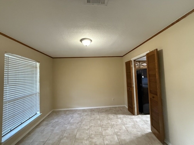 spare room with crown molding, plenty of natural light, a textured ceiling, and baseboards