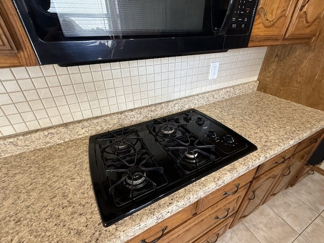 kitchen view of black appliances, brown cabinetry, and tasteful backsplash