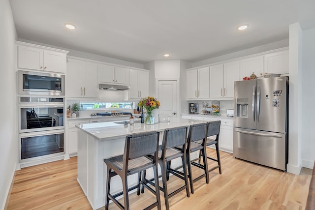 601 Wilderness Point Ln, Anna, TX 75409 - kitchen with appliances with stainless steel finishes, under cabinet range hood, white cabinets, a breakfast bar, and recessed lighting
