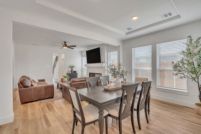 601 Wilderness Point Ln, Anna, TX 75409 - dining area featuring light wood-style floors, a glass covered fireplace, a tray ceiling, baseboards, and recessed lighting
