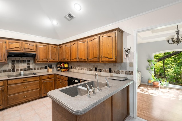 kitchen featuring under cabinet range hood, black appliances, brown cabinets, lofted ceiling, and a peninsula