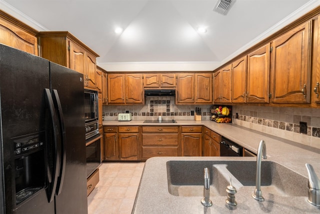 kitchen with black appliances, brown cabinets, vaulted ceiling, decorative backsplash, and light countertops