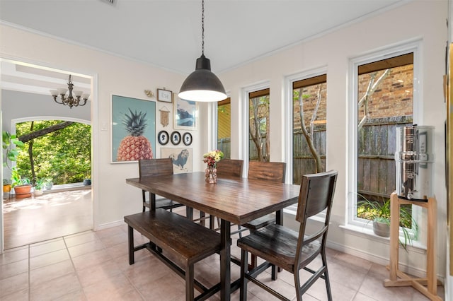 dining space with baseboards, ornamental molding, a chandelier, and light tile patterned flooring