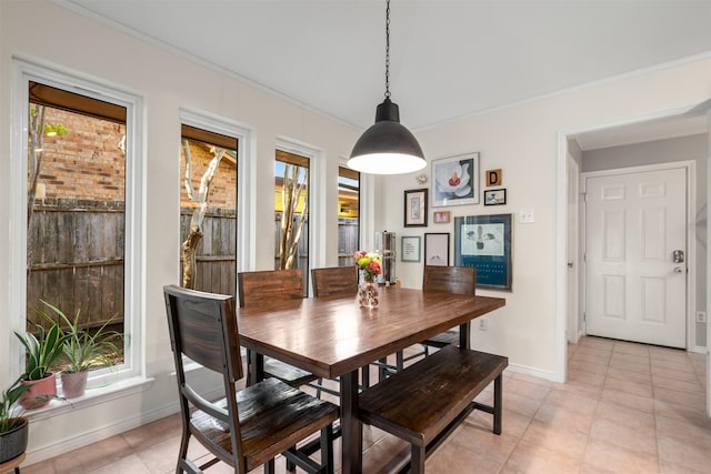 dining room featuring baseboards, crown molding, and light tile patterned flooring