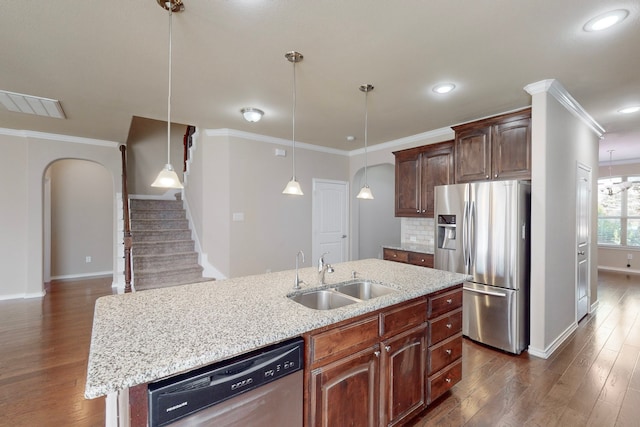 13013 Palancar Dr, Fort Worth, TX 76244 - kitchen featuring appliances with stainless steel finishes, a sink, baseboards, arched walkways, and dark wood-type flooring