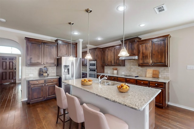13013 Palancar Dr, Fort Worth, TX 76244 - kitchen with appliances with stainless steel finishes, a sink, dark wood-style flooring, arched walkways, and crown molding